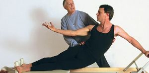 Ron Fletcher ensinando pilates no reformer a um aluno