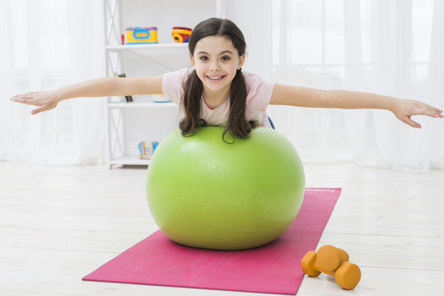 menina com bola realizando exercício de pilates para crianças