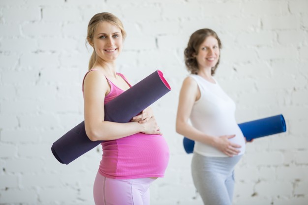 Mulheres grávidas com colchonete de pilates embaixo dos braços