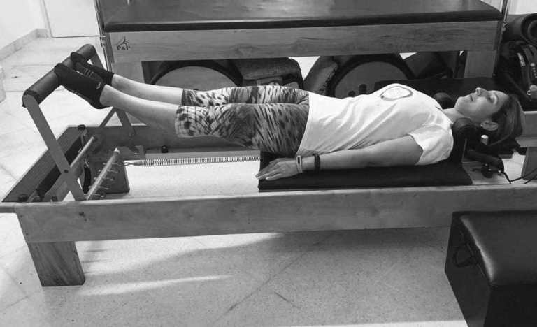 mulher realizando exercicio footwork no reformer de pilates