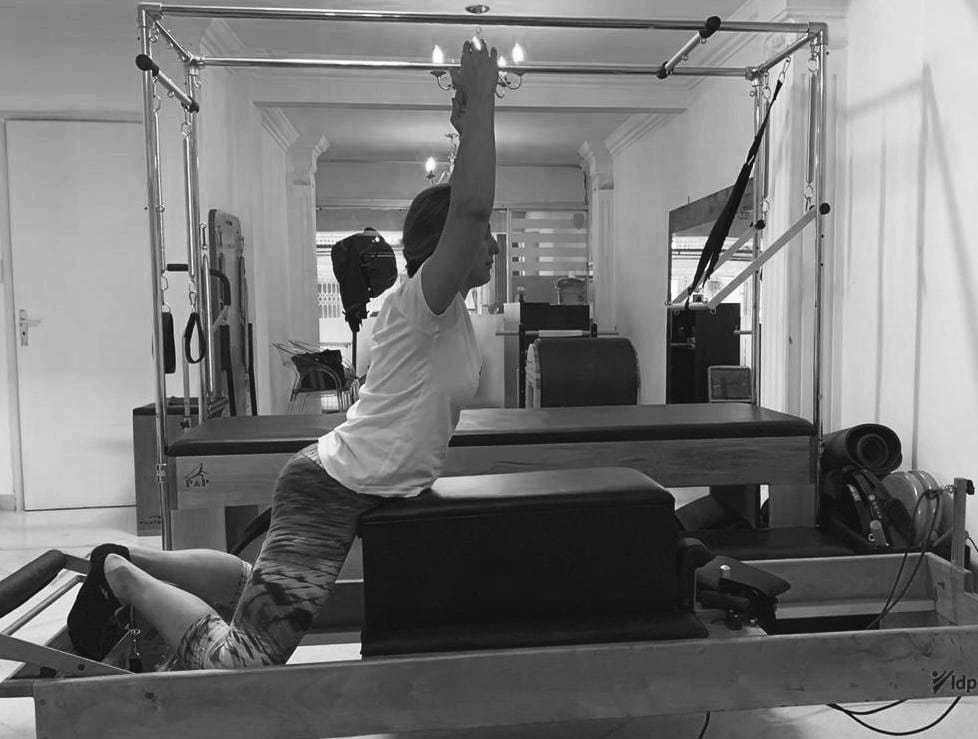 mulher realizando exercicio swan no reformer de pilates