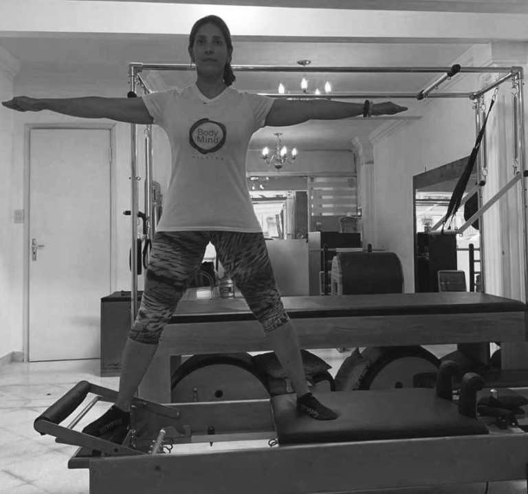 mulher realizando exercicio side split no reformer de pilates