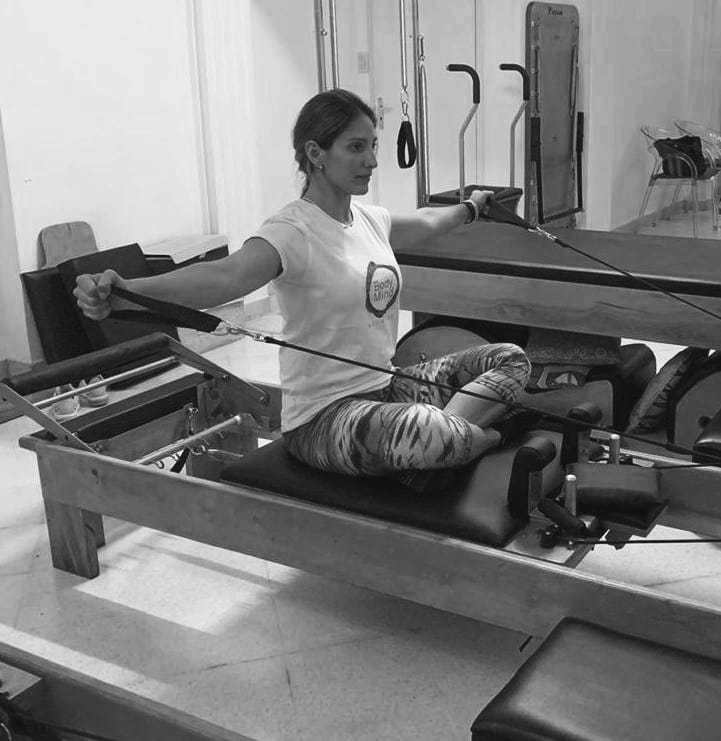 mulher realizando exercicio scapular aduction no reformer de pilates