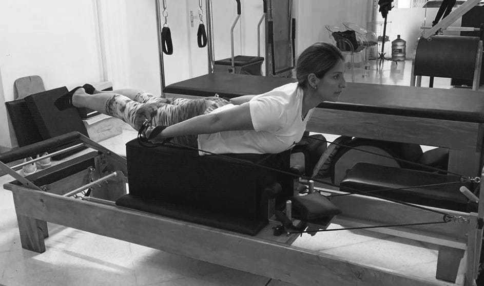 mulher realizando exercicio pilling straps  no reformer de pilates