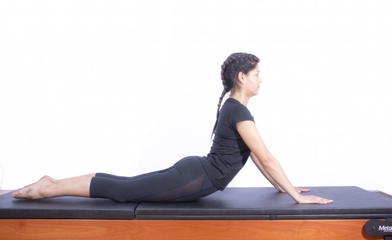 mulher realizando exercício swan de pilates