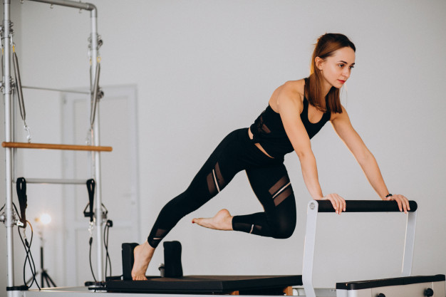 Mulher realizando exercício de pilates no Reformer