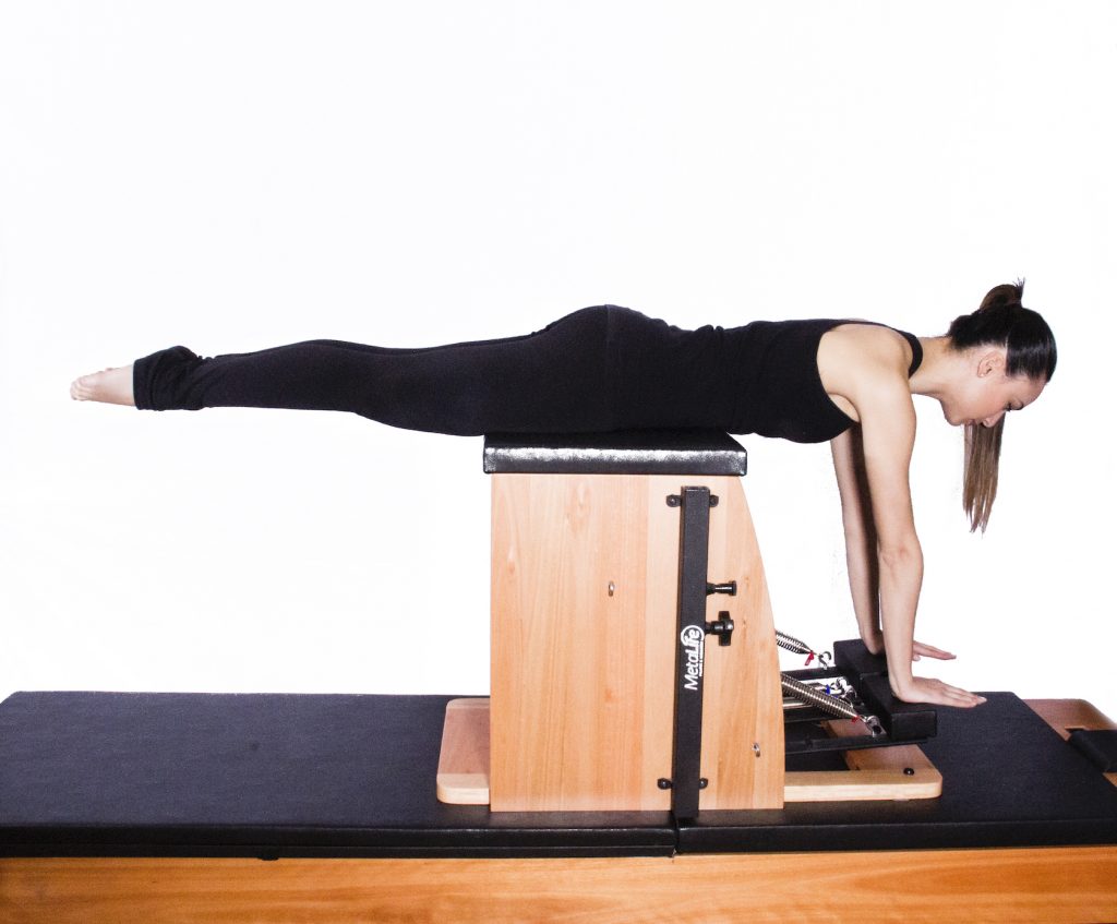 mulher em decúbito abdominal realizando exercício de pilates chair