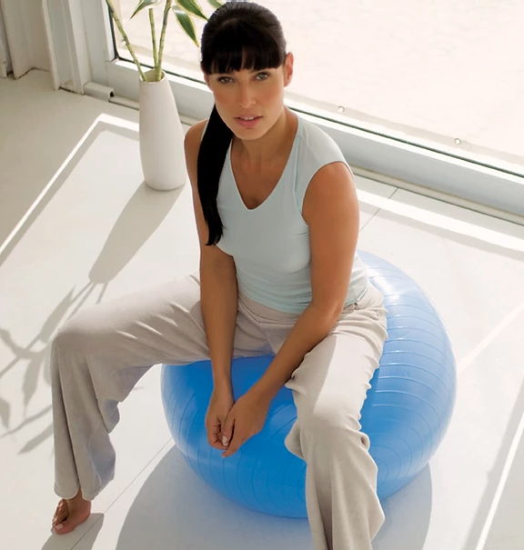 mulher sentada em acessório de pilates moderno conhecido como fitball ou stability ball
