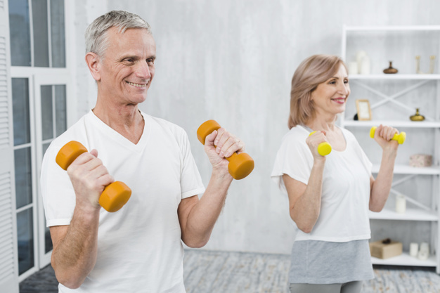 Homem e mulher de terceira idade com halteres nas mãos para prevenir sarcopenia