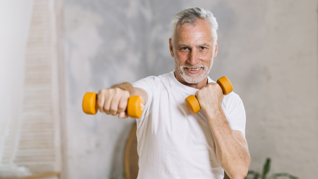 homem de terceira idade realizando exercício punch de pilates com halteres nas mãos