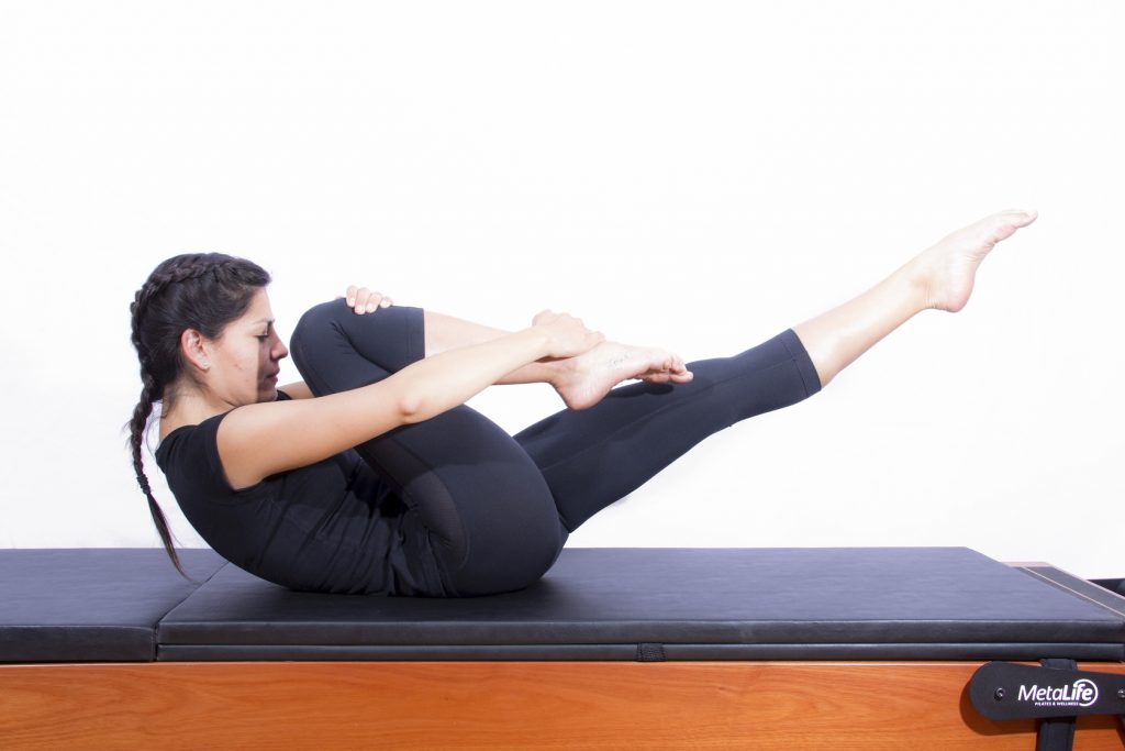 Mulher realizando exercício de pilates one leg stretch