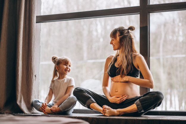 Mulher grávida y menina em aula de pilates
