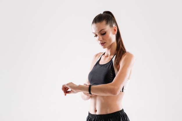 Mulher olhando o relógio para saber a hora de realizar pilates.