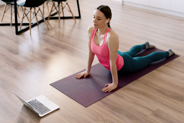 Mulher realizando exercício swan na aula de pilates online